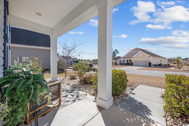 view of patio / terrace featuring a garage, covered porch, and a residential view