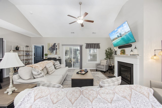 living room featuring ceiling fan, wood finished floors, high vaulted ceiling, and a glass covered fireplace