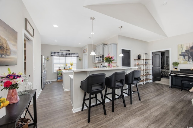 kitchen featuring wood finished floors, a breakfast bar, a peninsula, light countertops, and appliances with stainless steel finishes