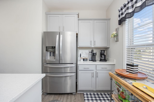 kitchen with light wood-style flooring, stainless steel fridge, gray cabinetry, and light countertops