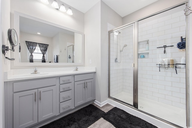 full bath featuring double vanity, a stall shower, and a sink