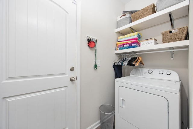 clothes washing area featuring baseboards, washer / clothes dryer, and laundry area