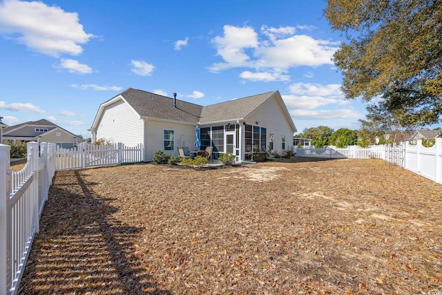 rear view of house featuring a fenced backyard and a sunroom