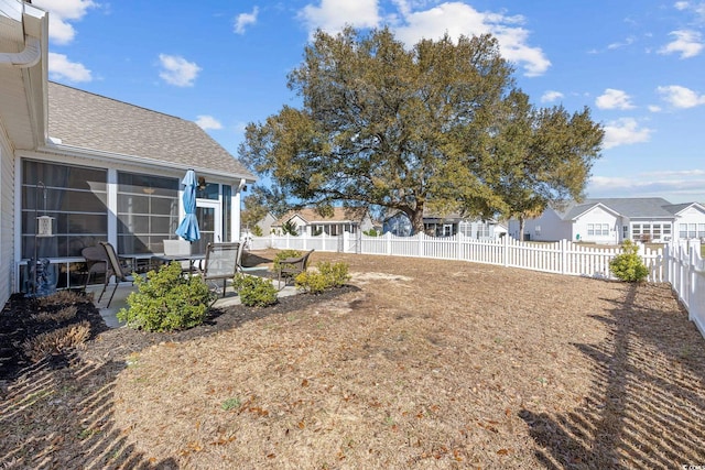 view of yard featuring a residential view, a sunroom, a fenced backyard, and a patio area