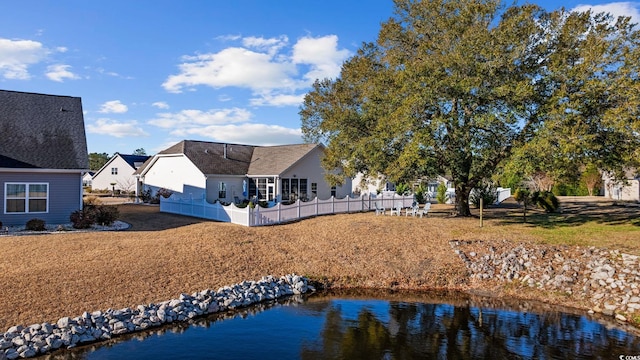 rear view of house with a water view and fence