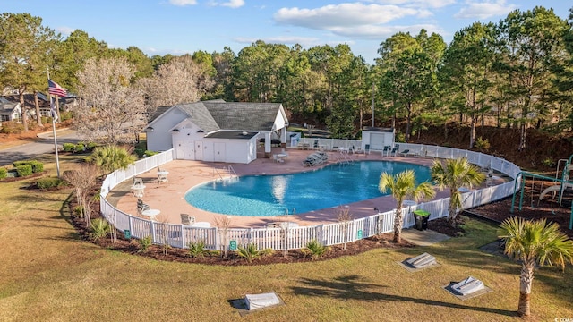 pool featuring a patio, an outbuilding, a lawn, and fence