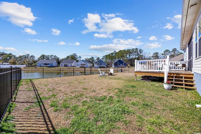 view of yard featuring a fenced backyard, a deck with water view, and a residential view