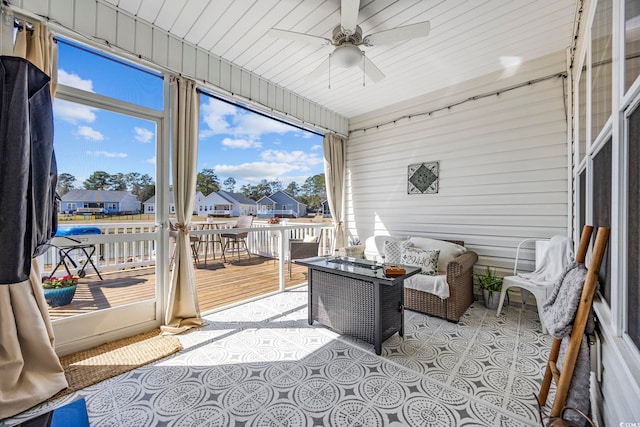 sunroom / solarium with a residential view and ceiling fan