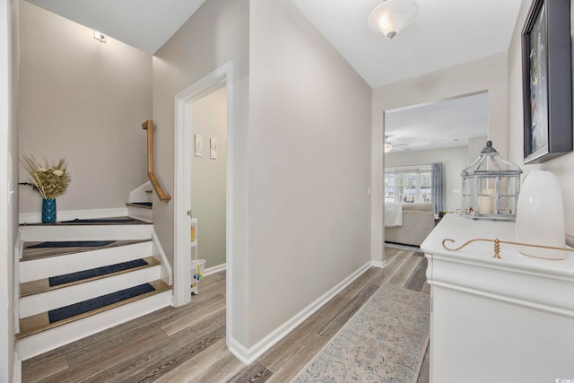 hallway with stairway, wood finished floors, and baseboards