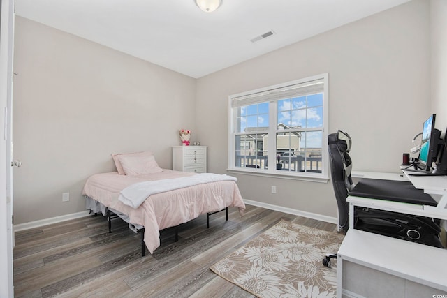 bedroom featuring visible vents, baseboards, and wood finished floors