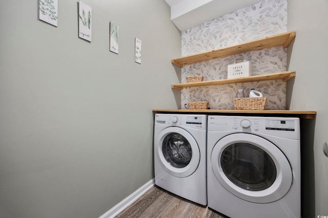 clothes washing area with laundry area, wood finished floors, baseboards, and washing machine and clothes dryer