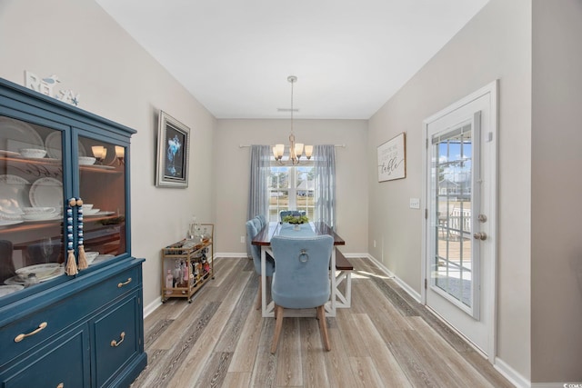 dining area featuring visible vents, a notable chandelier, light wood-style floors, and baseboards