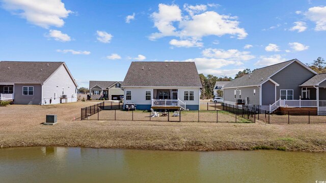 rear view of property featuring a fenced backyard and a water view