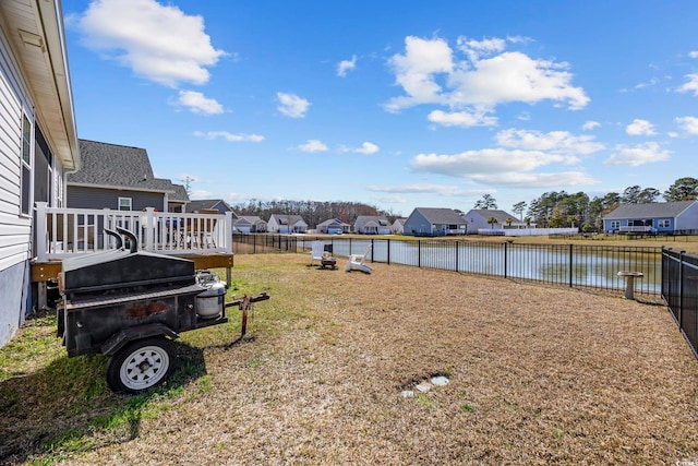 view of yard featuring a residential view, a deck with water view, and a fenced backyard