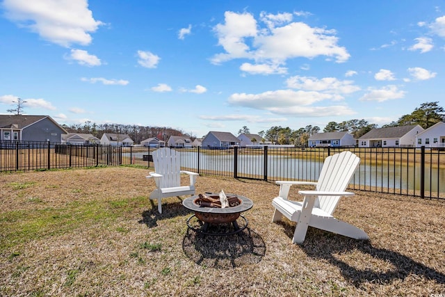 view of yard featuring a residential view, fence, a water view, and an outdoor fire pit