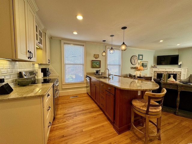 kitchen with a kitchen breakfast bar, light wood finished floors, appliances with stainless steel finishes, and a sink