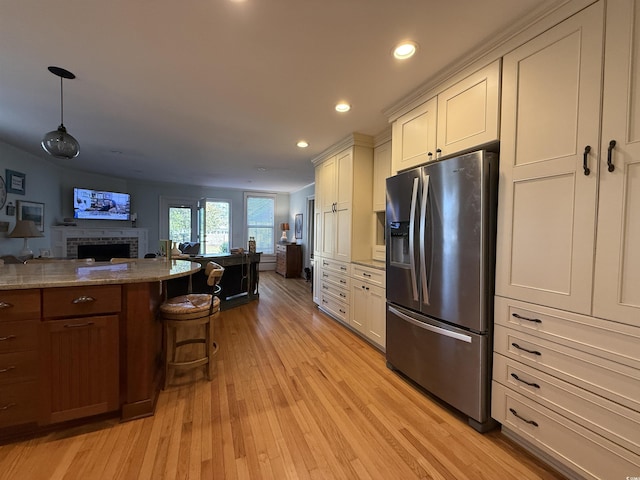 kitchen with open floor plan, a kitchen bar, recessed lighting, light wood-style flooring, and stainless steel fridge