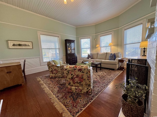 living room featuring wainscoting, a fireplace, crown molding, and hardwood / wood-style floors