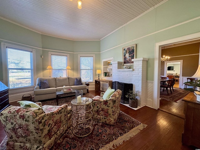 living area with a fireplace, crown molding, an inviting chandelier, and hardwood / wood-style floors