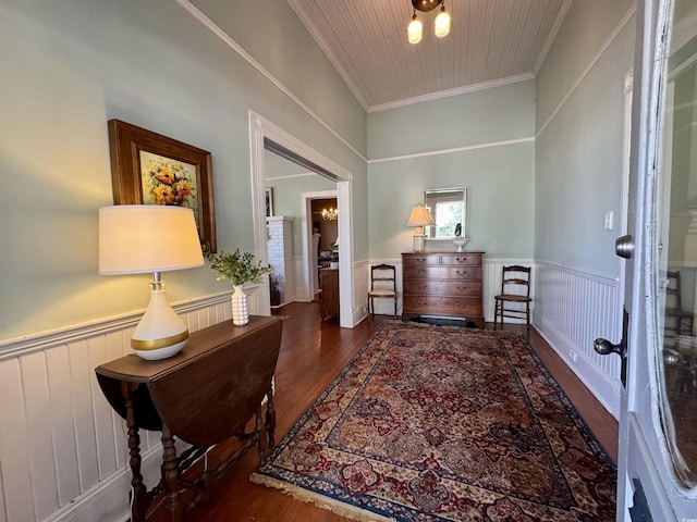 foyer entrance featuring a notable chandelier, ornamental molding, wood finished floors, radiator, and wainscoting