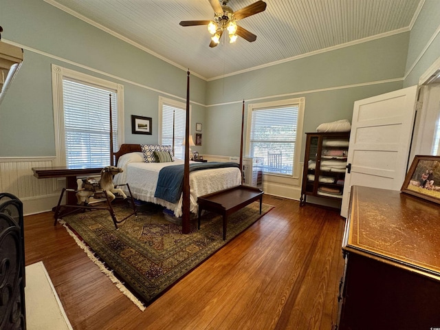 bedroom with wainscoting, dark wood-type flooring, ornamental molding, and a ceiling fan