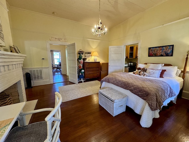 bedroom with visible vents, a notable chandelier, hardwood / wood-style floors, and a fireplace