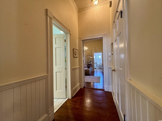 hall with dark wood finished floors, wainscoting, and ornamental molding