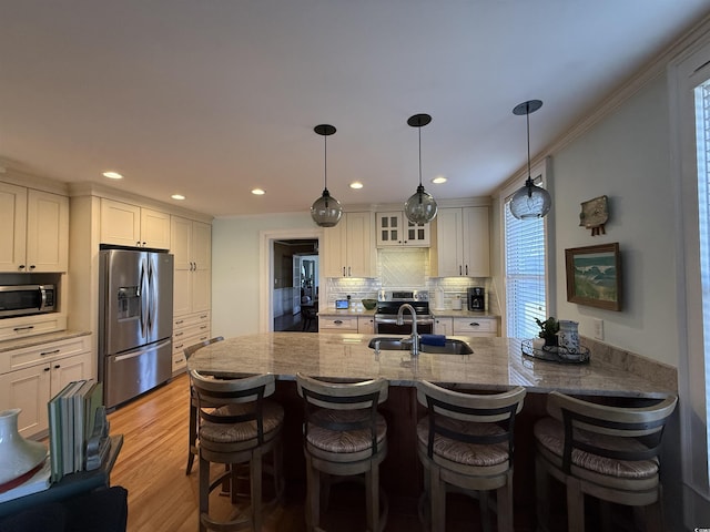 kitchen with light wood-style flooring, a sink, backsplash, appliances with stainless steel finishes, and white cabinets