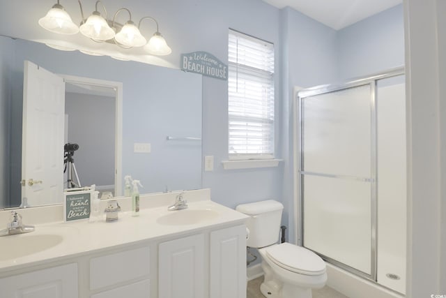 bathroom with a sink, toilet, a stall shower, and double vanity