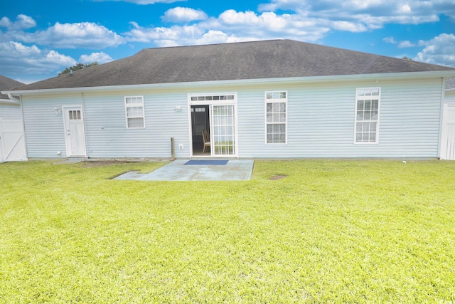 back of house featuring a lawn, a shingled roof, and a patio area