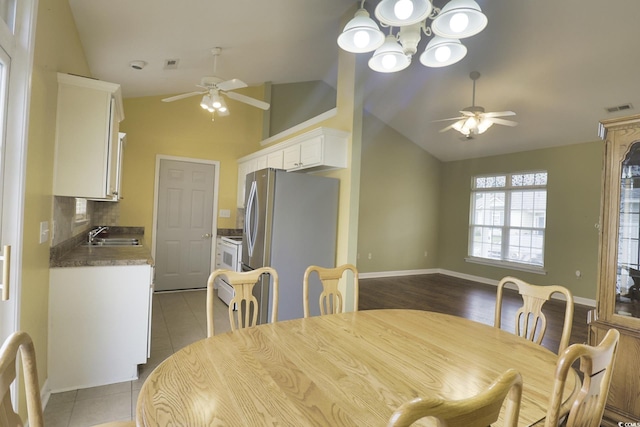 dining space with light tile patterned floors, visible vents, vaulted ceiling, and ceiling fan with notable chandelier