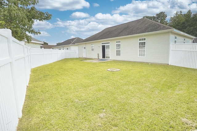 rear view of house with a patio area, a yard, a fenced backyard, and roof with shingles