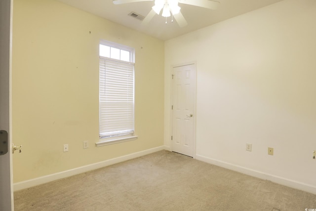 carpeted empty room with baseboards, visible vents, and ceiling fan