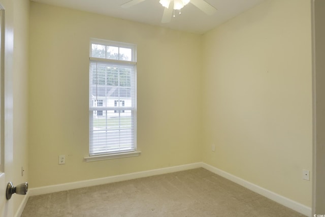 spare room featuring light colored carpet, baseboards, and a ceiling fan