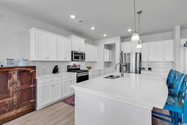 kitchen featuring visible vents, a sink, stainless steel appliances, light countertops, and light wood-type flooring