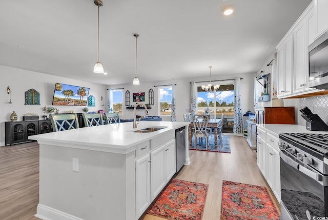 kitchen with stainless steel appliances, a sink, light countertops, white cabinetry, and light wood-type flooring