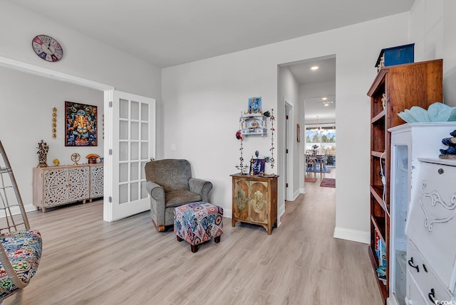 sitting room with light wood finished floors, french doors, and baseboards