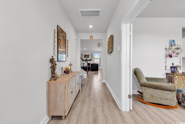 corridor with visible vents, light wood-style flooring, and baseboards