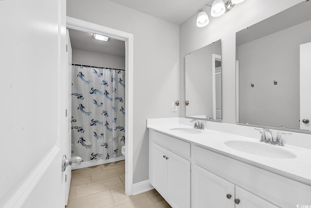 bathroom featuring double vanity, toilet, a shower with curtain, and a sink