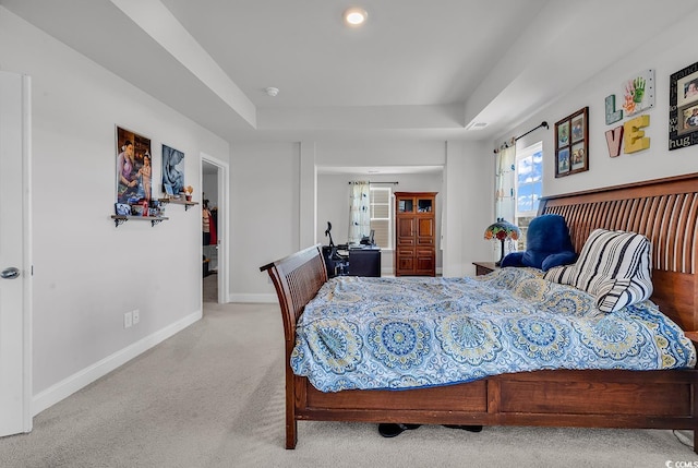 bedroom with a tray ceiling, baseboards, and light colored carpet