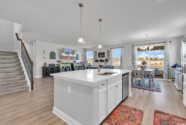 kitchen featuring stainless steel dishwasher, an island with sink, light wood-type flooring, and a sink