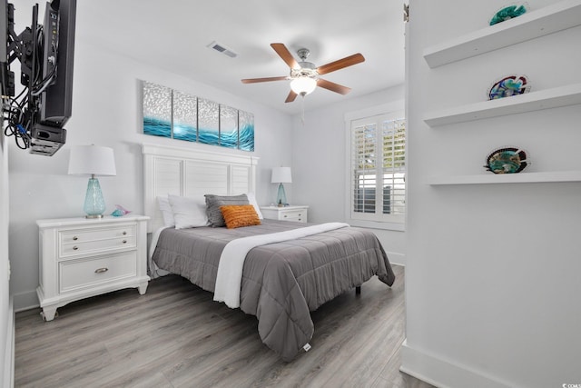 bedroom featuring a ceiling fan, light wood-style floors, visible vents, and baseboards