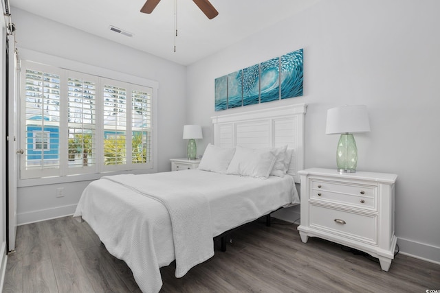 bedroom with ceiling fan, visible vents, baseboards, and wood finished floors