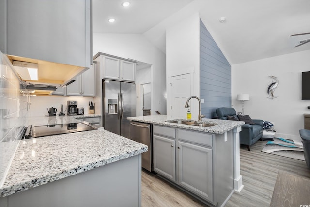 kitchen with open floor plan, lofted ceiling, gray cabinets, appliances with stainless steel finishes, and a sink