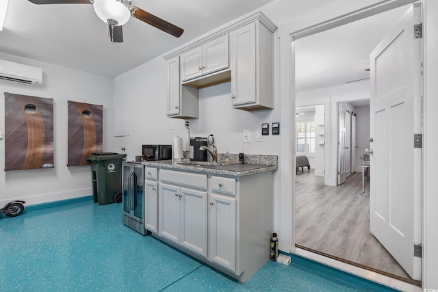 kitchen featuring beverage cooler, baseboards, an AC wall unit, and ceiling fan