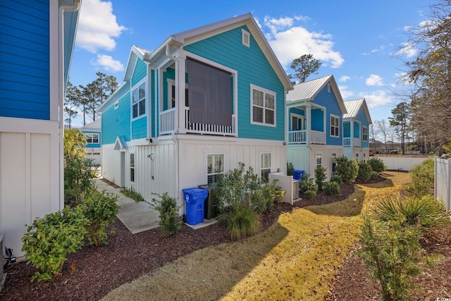 exterior space featuring a standing seam roof, fence, board and batten siding, and metal roof