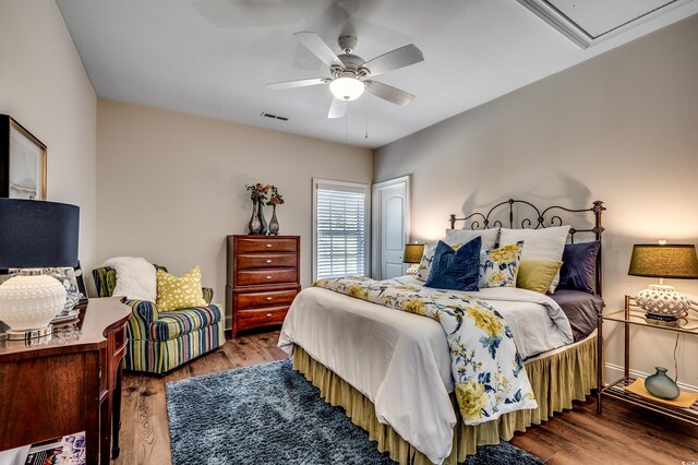 bedroom with visible vents, attic access, wood finished floors, and a ceiling fan