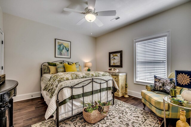 bedroom with ceiling fan, visible vents, baseboards, and wood finished floors