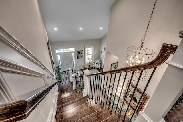 staircase featuring recessed lighting, an inviting chandelier, and hardwood / wood-style flooring