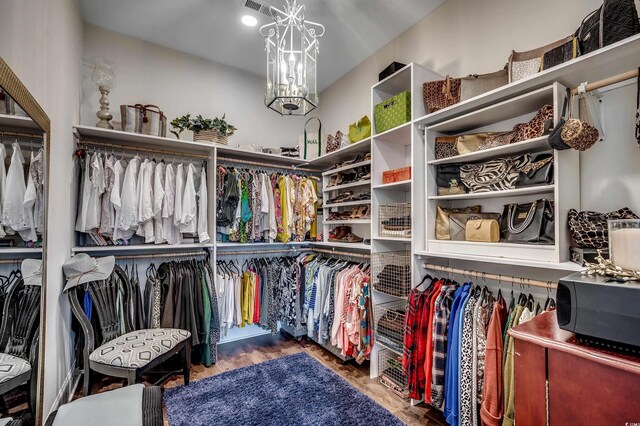 walk in closet with visible vents, an inviting chandelier, and wood finished floors